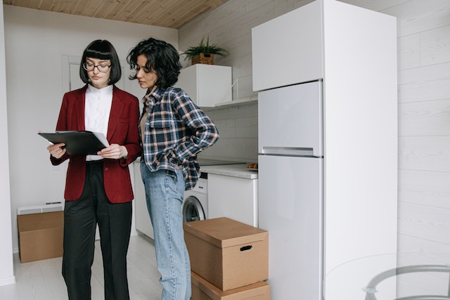 a landlord in a red jacket looking at checklist with a tenant in a blue flannel